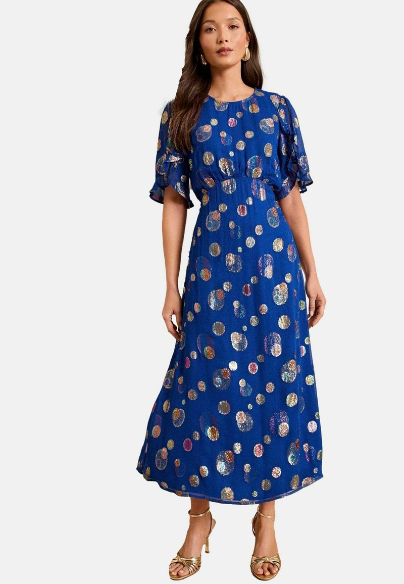 Zila maxi kleita ar īsām krauklītēm, kurai ir metāliski punktiņi dažādās krāsās. Gluda auduma, ar brīvu piegriezumu, līdz teļu garumam.