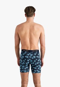 Navyblauwe boxershorts van katoen, met een lichtblauw palmenpatroon. Elastische tailleband met de tekst "HAPPY SHORTS".