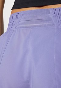 Lila byxor med en mjuk textur, som har en samlad elastisk midjeresår och subtila sömdetaljer på baksidan.