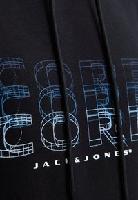 Zwarte sweatshirt met een blauw geometrisch ontwerp en witte tekst die "JACK & JONES" zegt. Zacht stof met een trekkoorddetail.