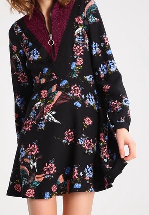 Robe à motif floral en tissu noir avec un décolleté profond en V, dotée d'un col bordeaux scintillant et de manches longues.