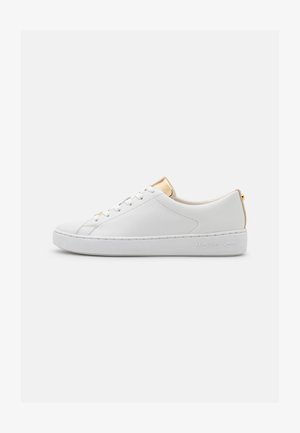 Witte leren sneaker met een ronde neus, gouden metalen accenten op de hiel en tong, en een dikke witte zool met reliëfbranding.