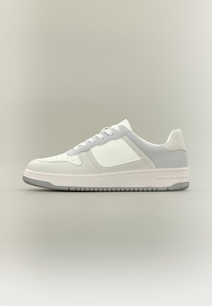 Low-top white and light gray sneaker with perforated toe, lace-up closure, and textured rubber sole on neutral background.