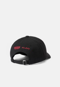 Melnā beisbola cepure ar regulējamu siksniņu. Uzraksts ar sarkanu izšuvumu: "STRANGER THINGS" un "ALDO" aizmugurē. Mīksta auduma tekstūra.