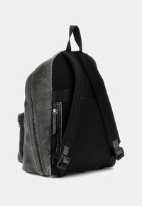 Zaino nero con un'esterno in similpelle testurizzato, pannelli in rete, spallacci imbottiti e una tasca laterale con zip. Presenta cuciture resistenti.