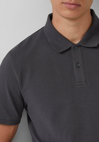 Donkergrijze polo-shirt gemaakt van gestructureerde stof, met een klassieke kraag en een drie-knopen sluiting, met een eenvoudig en schoon ontwerp.