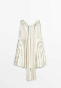 Blouse blanche plissée sans manches avec un lien autour du cou et un détail dos ouvert, présentée sur fond blanc uni.