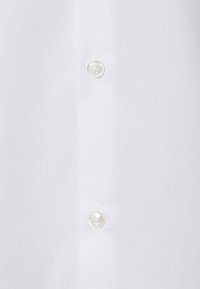 Chemise blanche à boutons, dotée d'un tissu lisse et infroissable, avec des boutons en plastique transparent le long de la patte de boutonnage avant.