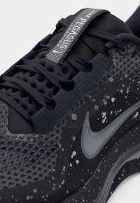 Nike Pegasus tekačeva obuća z temno sivo mrežico na zgornjem delu, teksturiranimi poudarki, sivim swooshom, odsevnimi oznakami in pegastimi detajli.