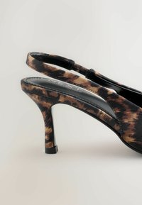 Černé a hnědé slingback sandály na podpatku s hladkou texturou, úzkým podpatkem a polstrovanou stélkou s jemným značením.