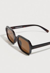 Ορθογώνια γυαλιά ηλίου με σκούρο πλαίσιο τύπου χελώνας, καφέ φακούς και διακριτικό λογότυπο στο πλαϊνό μέρος, με φαρδιά μπράτσα και γυαλιστερό φινίρισμα.