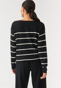 Bluză cu mânecă lungă în dungi alb-negru, cu o croială lejeră și decolteu larg, având manșete și tiv ribbate, fabricată dintr-un material moale.