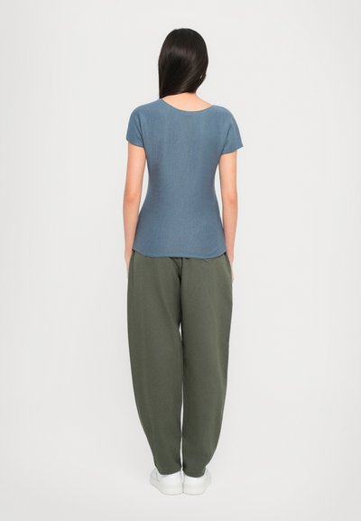 Blue ribbed t-shirt with short sleeves, round neckline; paired with loose olive-green trousers and white sneakers.