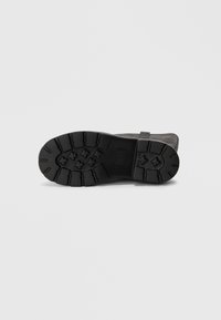 Black rubber sole with a textured tread pattern and rounded edges, featuring a raised logo and a sleek, minimalist design.