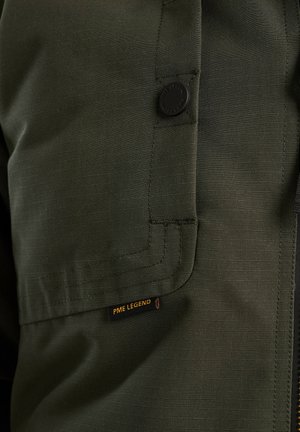 Groene stoffen jas met een gestructureerd oppervlak, een opvallende zwarte knop en een zichtbaar PME Legend label met gele letters.
