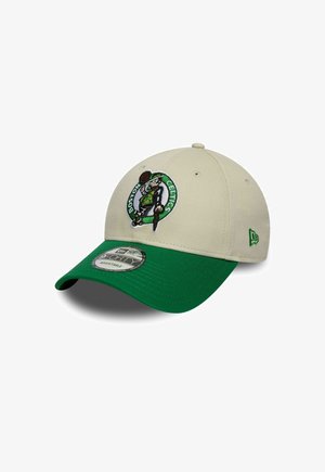 Gorra beige con visera verde, que presenta un logotipo bordado de los Boston Celtics en la parte delantera. Está hecha de tela y cuenta con una correa trasera ajustable.