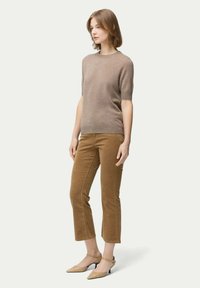 Brun kortärmad tröja med en slät yta, i kombination med tanfärgade manchesterbyxor i cropped-stil och beige ankelsandaler.