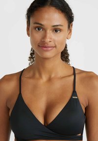Zwart bikini-top met een trapeziumvormig ontwerp, dunne bandjes en een klein goudkleurig logoaccent. Gladde textuur en een minimalistische bedekkingsstijl.