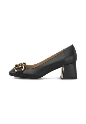 Zapatos de charol negro con tacón bloque y punta redondeada, que presentan un acento de metal en tono dorado en la parte frontal y una textura suave.