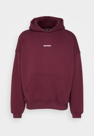Bordeauxrode hoodie met capuchon, voorzak in kangoeroestijl en witte tekst "WRSTBHVR" in het midden van de borst.