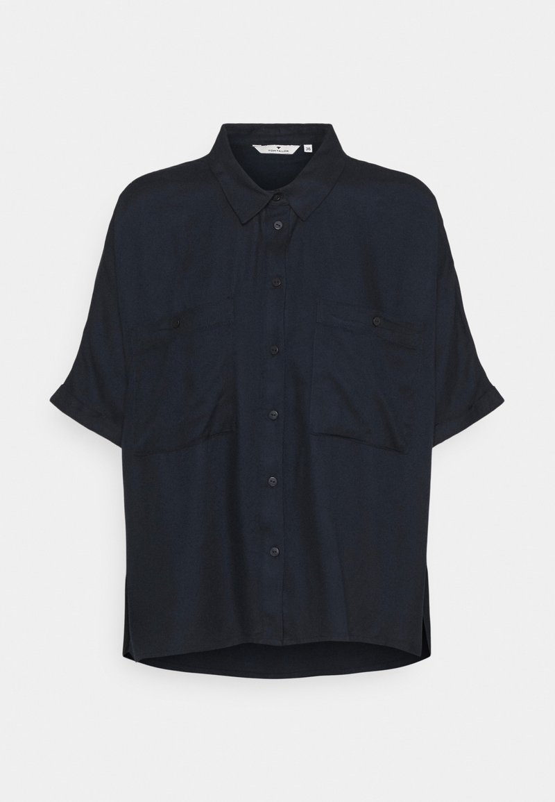 Mörk marinblå kortärmad blus, avslappnad passform, knäppning framtill, krage, två bröstfickor, sidovolanger, tillverkad av lätt tyg.