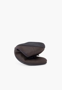 Calzado negro tipo mocasín con una superficie suave y texturizada y un diseño flexible. Presenta una puntera redondeada y un estilo minimalista.
