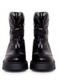 Botas de tobillo acolchadas en negro con un acabado brillante, que presentan una textura acolchada, suelas de goma, cordones ajustables y una etiqueta con el logo en el costado.