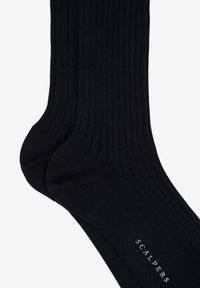 Calcetines negros de canalé hechos de una suave mezcla de algodón con talón y puntera reforzados. Presentan el nombre de la marca "SCALPERS" impreso cerca del tobillo.