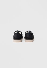 Scarpe slip-on nere con retro arrotondato, tomaia in tessuto testurizzato, rivestimento crema e suola spessa in gomma beige.
