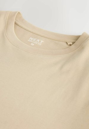 Smėlio spalvos medvilninis marškinėliai su apvalia iškirpte, ant kurios matyti etiketė „NEXT Regular Fit M“ vidinėje apykaklės pusėje.