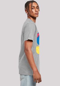 Pelēks kokvilnas T-krekls ar krāsainu ilustrētu dizainu, ar ziliem, rozā un dzelteniem akcentiem. Īsas piedurknes un brīvs piegriezums.