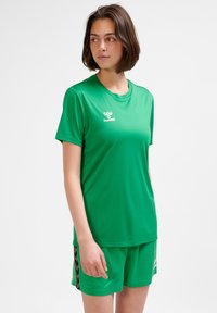 Zielona sportowa koszulka z gładkiej tkaniny, z okrągłym dekoltem i krótkimi rękawami, w zestawie z dopasowanymi szortami z bocznymi akcentami.