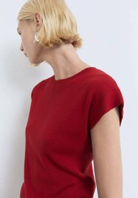 Top rosso lavorato a maglia con maniche corte e scollatura rotonda. Texture liscia e design aderente, che mette in risalto una silhouette pulita.