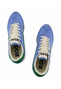 Lichtblauwe suède sneakers met groene accenten, crèmekleurige veters en zwarte zolen. Het interieur bevat een patroon op de binnenzool met 'roots' bedrukt.