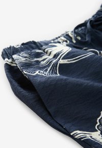 Marinblå tygshorts med en texturerad yta, prydda med ett vitt abstrakt mönster och en elastisk midja för justerbar komfort.