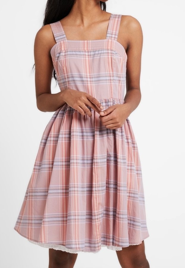 Różowa sukienka w kratkę, wykonana z lekkiego materiału, z kwadratowymi ramiączkami, dopasowanym gorsem i rozkloszowaną spódnicą z koronkowym wykończeniem u dołu.