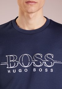Marinblå crew neck sweatshirt i mjukt tyg. Har en vit broderad "BOSS" logotyp med "HUGO BOSS" under. Korta ärmar.