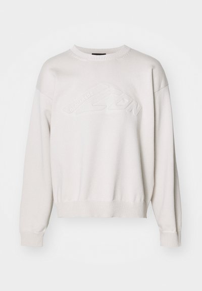 Sweatshirt en tricot blanc avec un col rond et un ourlet côtelé. Présente un design de logo texturé à l'avant et des manches tombantes.