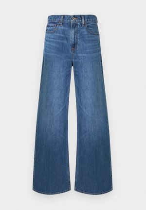 Jean denim bleu à jambes larges avec bouton avant et fermeture éclair, style cinq poches, et passants pour ceinture, présenté sur un fond blanc.