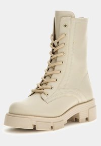 Beige lace-up combat boot with a smooth leather finish, chunky rubber sole, and reinforced stitching details.  Mid-calf height.