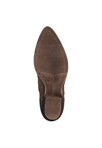 Semelle de chaussure brune avec une forme pointue, une surface texturée et des bords cousus. Étiquette de taille "37" visible près du talon.