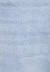 Tela de mezclilla de color azul claro con un tejido de sarga, que presenta una textura suave y un sutil desgaste, con un enfoque en el patrón diagonal.