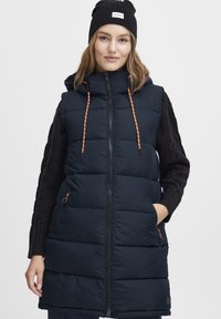 Marintröja med huva, orange dragsko, blixtlåsfickor och en avslappnad passform. Texturerade svarta stickade ärmar synliga.