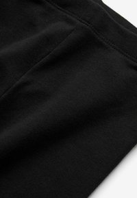 Tessuto nero con una morbida texture, caratterizzato da una superficie liscia e un sottile dettaglio di cucitura. Il materiale sembra leggero ed elasticizzato.