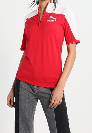 Red athletic shirt with a white collar and sleeves, short zip, and Puma logo on the chest. Material appears smooth and breathable.