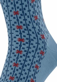 Blauer Socken mit vertikalen dunkelblauen karierten Streifen und verstreuten roten Sternmuster, Nahaufnahme der Stoffstruktur und des Designs.