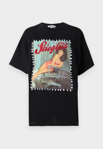 Camiseta de algodón negra con un estampado vintage colorido de una mujer en una silla, bordeado por un patrón a rayas. Cuello redondo, corte relajado.