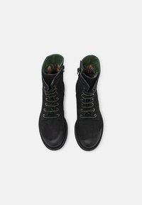 Bottes noires en cuir à la cheville avec des lacets verts, tige texturée, bout arrondi et doublure en tissu rayé. Fermeture éclair latérale pour un accès facile.