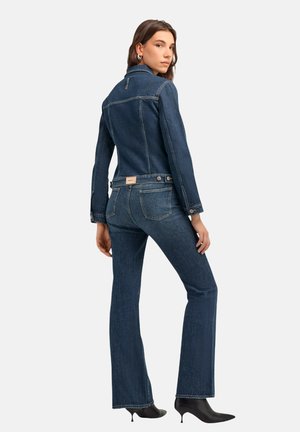 Giacca in denim scuro e jeans svasati con una silhouette aderente. Presentano cuciture sottili, due tasche posteriori e un'etichetta con il marchio sulla vita.