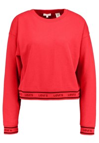 Červená zkrácená mikina vyrobená z měkké tkaniny, s dlouhými rukávy a černým lemem na spodním okraji se opakovaným logem "Levi's".
